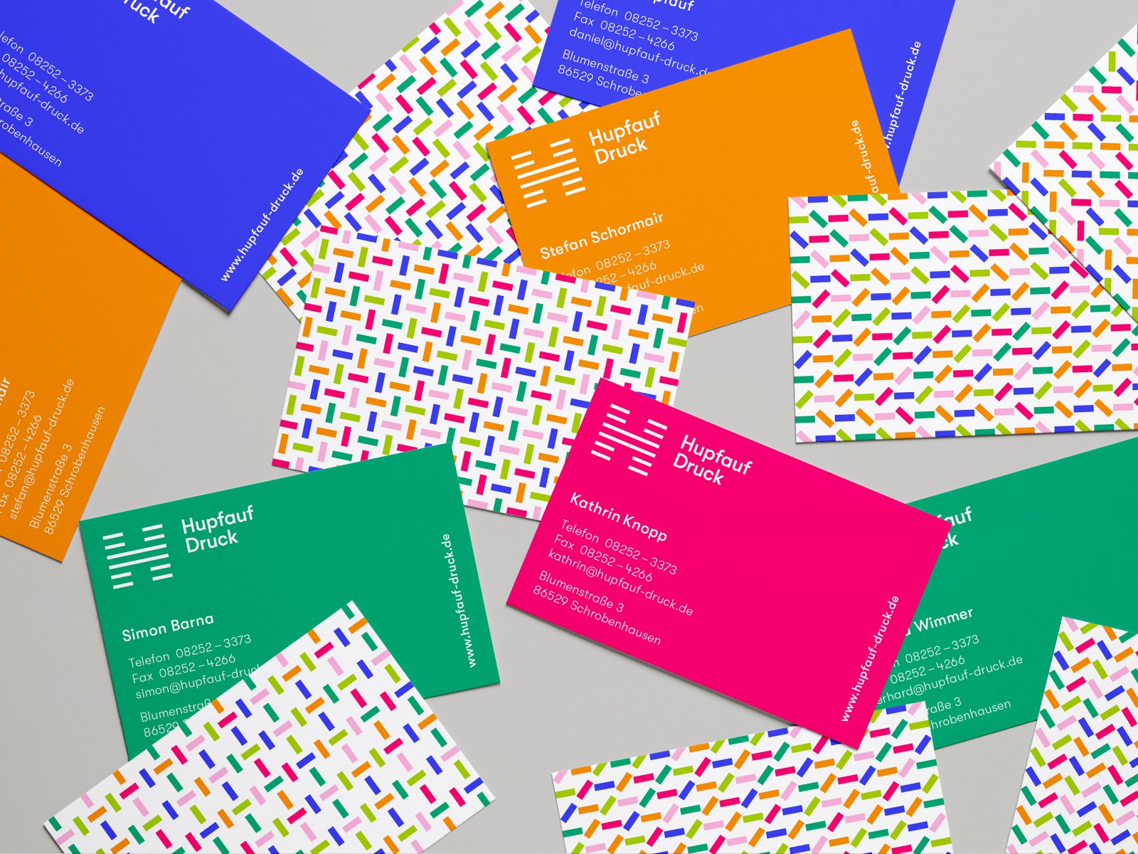 Visitenkarten von Hupfauf Druck in Orange, Grün, Blau und Pink mit buntem Konfetti-Logo-Muster auf der Rückseite