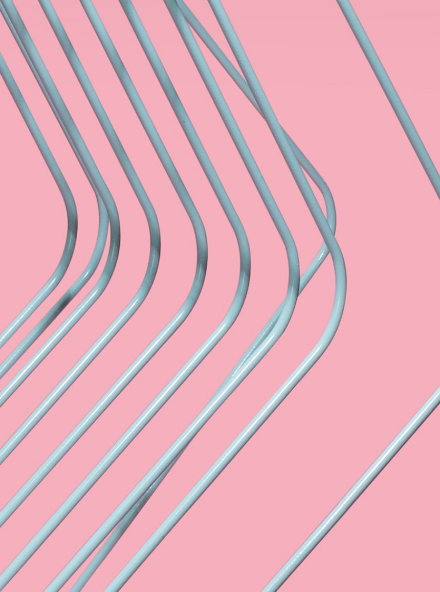 Close-up of a minimalist metal wire-frame chair against a pink background