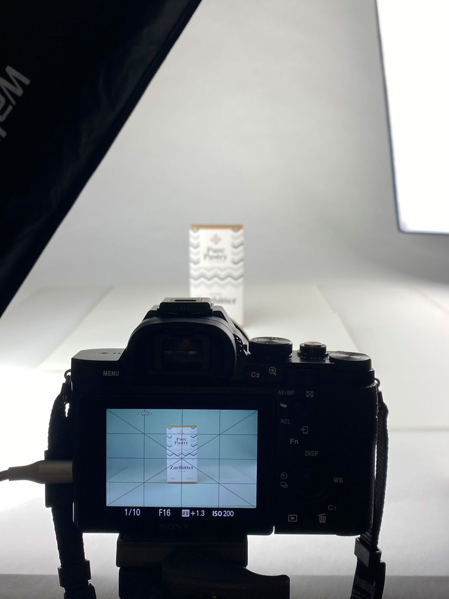 Kamera auf Stativ richtet sich auf ein Pure Pastry Produkt im Fotostudio, Display zeigt Vorschau.